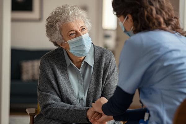 home health care professional holding hands with elderly woman